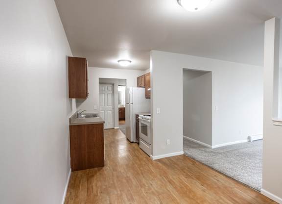 a living room and kitchen with wood floors and white walls