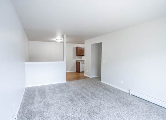 an empty living room with a white wall and carpet