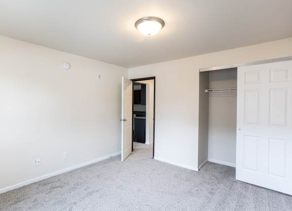 an empty bedroom with a closet and a door to a bathroom