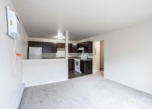 a renovated living room and kitchen with white carpet and black cabinets