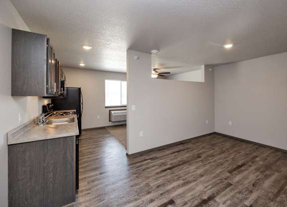 A kitchen with dark wood floors and a black refrigerator.