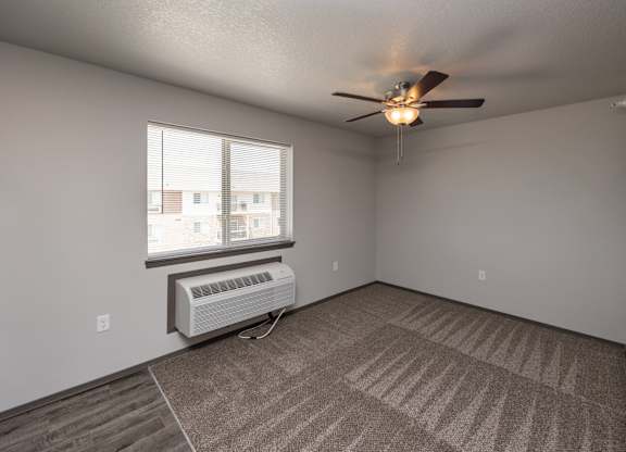 A room with a ceiling fan and carpeted floor.