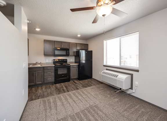 A well-lit, empty room with a kitchenette and a window.