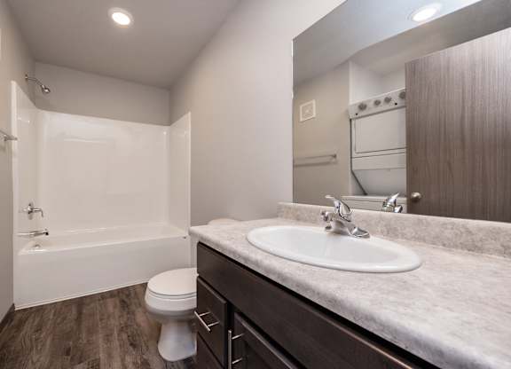 A white toilet is in a bathroom with a sink and a bathtub.