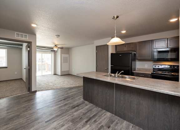 A kitchen with a black refrigerator and a sink.