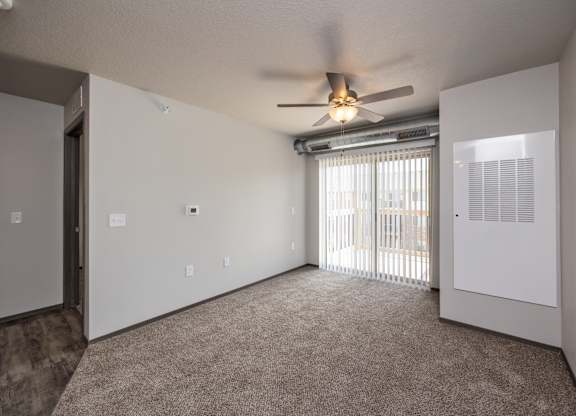 A room with a ceiling fan and a window with blinds.