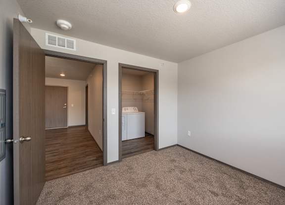A white washing machine is in a small room with a brown carpet.