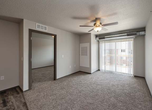 A room with a ceiling fan and sliding glass doors.
