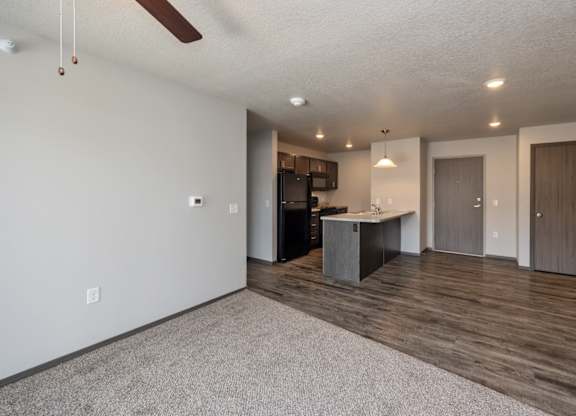 A spacious room with a kitchen area and a ceiling fan.