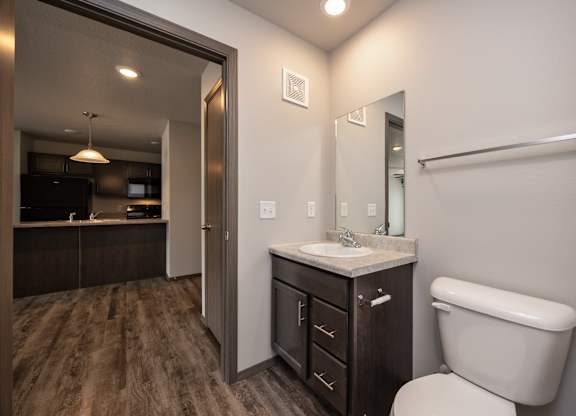 A bathroom with a toilet, sink, and mirror.