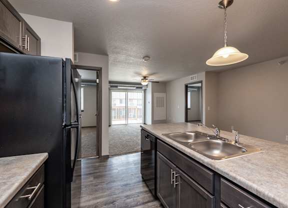 A kitchen with a black refrigerator and a marble countertop.