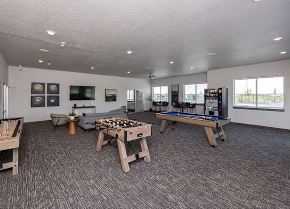 A room with a pool table, air hockey table, foosball table, and a shuffleboard table.