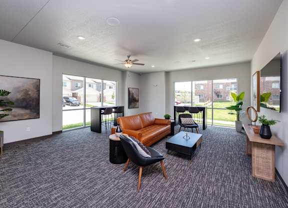 A spacious living room with grey carpeting and furniture.