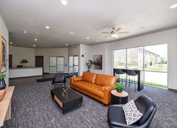 A spacious living room with a brown sofa, a black coffee table, and a ceiling fan.