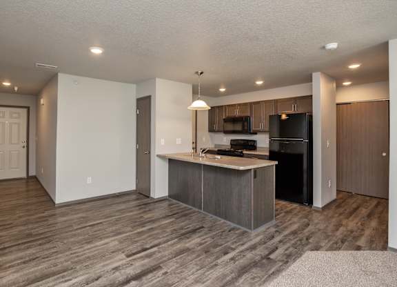 A kitchen with a black refrigerator and microwave, and a white countertop.