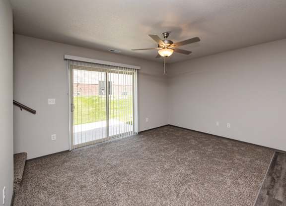 A room with a ceiling fan and sliding glass doors.