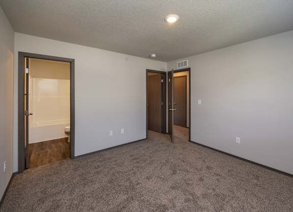 A room with carpeted floor and two doors.