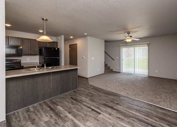 A spacious kitchen with dark wood cabinets and a black refrigerator.