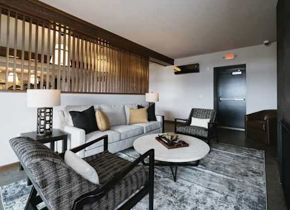 A living room with a grey rug and a white couch.