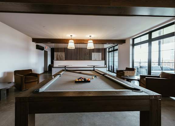 A pool table is in the middle of a room with a couch and a chair.