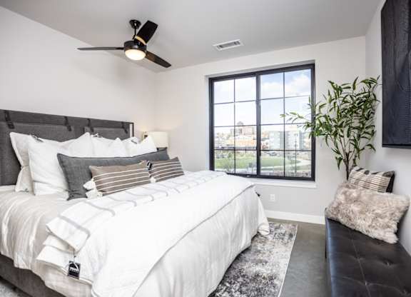 A bedroom with a large bed and a window overlooking a cityscape.
