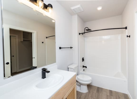 A white bathroom with a toilet, sink, and mirror.