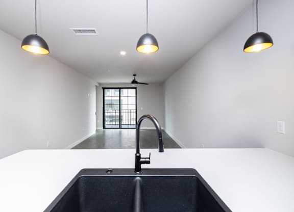 A modern kitchen with a black sink and pendant lights.