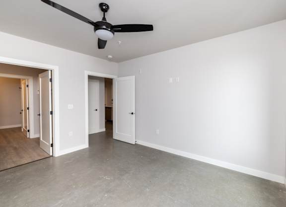 a living room with white walls and a ceiling fan