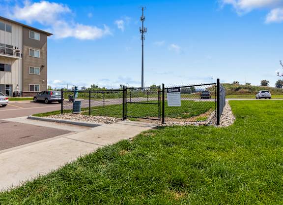 A sign is posted on a fence in front of a grassy area.
