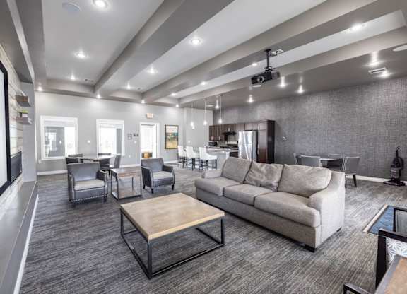 A modern living room with grey carpeting and furniture.