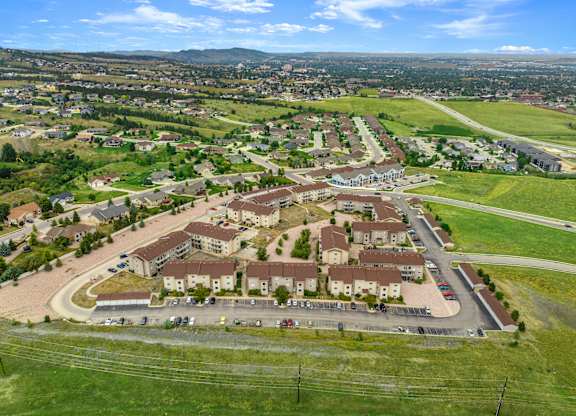 A large, modern housing complex with a parking lot in the foreground.