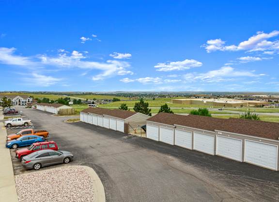 A parking lot with cars and a long row of garages.