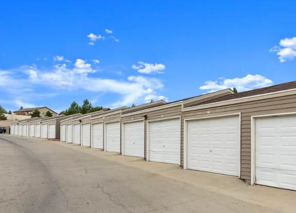 A row of white garage doors in front of a building.