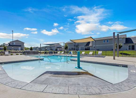 A large outdoor swimming pool with a diving board and lounge chairs.