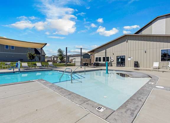 A large outdoor swimming pool with a diving board and lounge chairs.