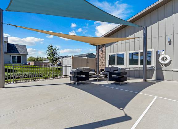 A patio area with a white wall and a black sofa.