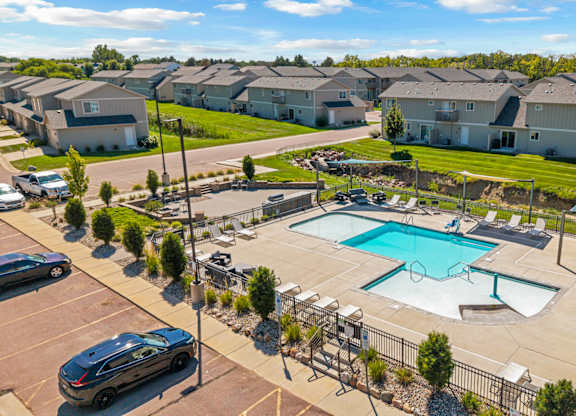 A swimming pool in a residential area surrounded by houses and cars.