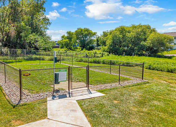 A green fenced area with a gate and a small building.