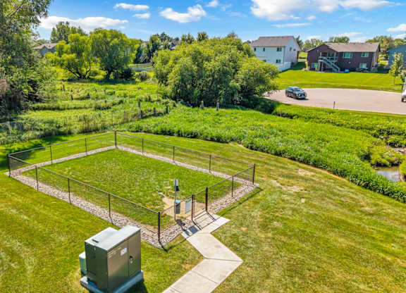 A green field with a fence and a small building in the middle.