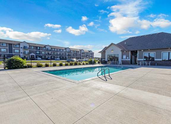 A swimming pool in a concrete pool area with a building in the background.