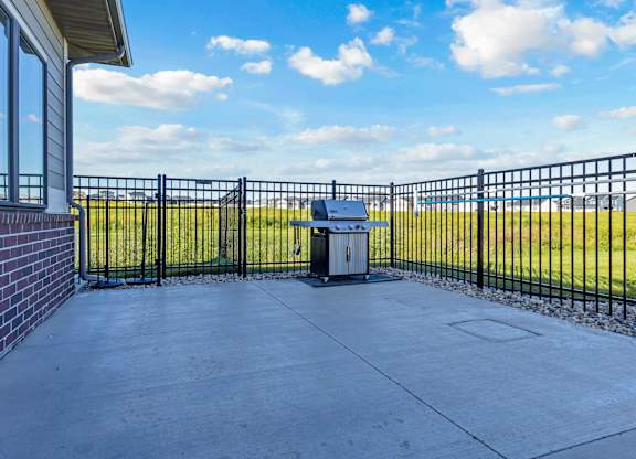 A black metal fence surrounds a concrete patio with a trash can in the middle.