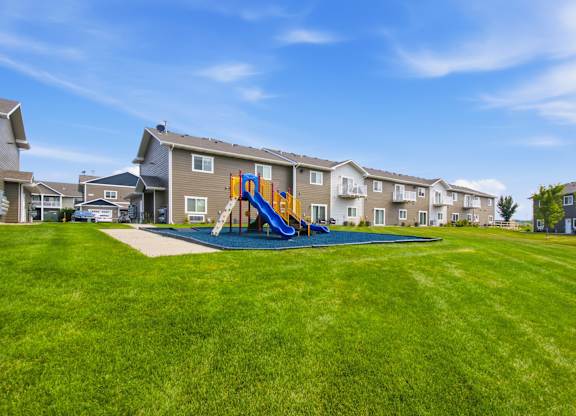 A playground with a blue slide is in the foreground of a residential area.