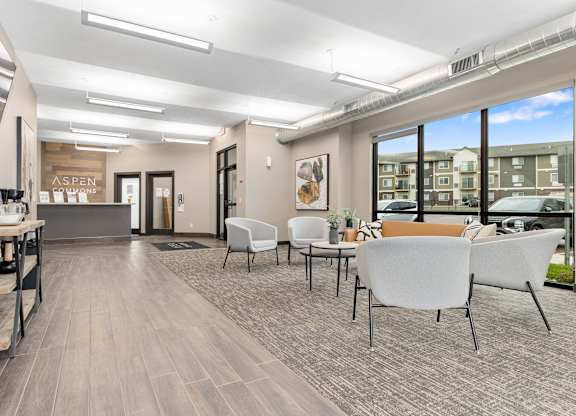 A spacious waiting area with white chairs and a wooden floor.