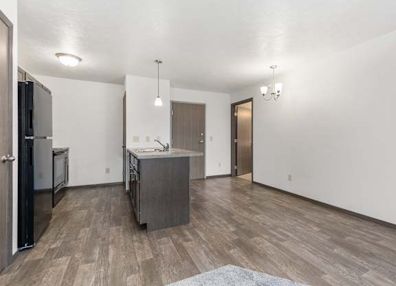 A kitchen with a refrigerator, sink, and cabinets.