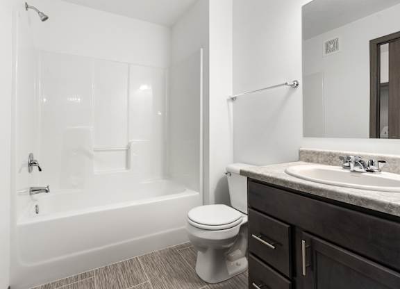 A white toilet sits next to a white bathtub in a bathroom.