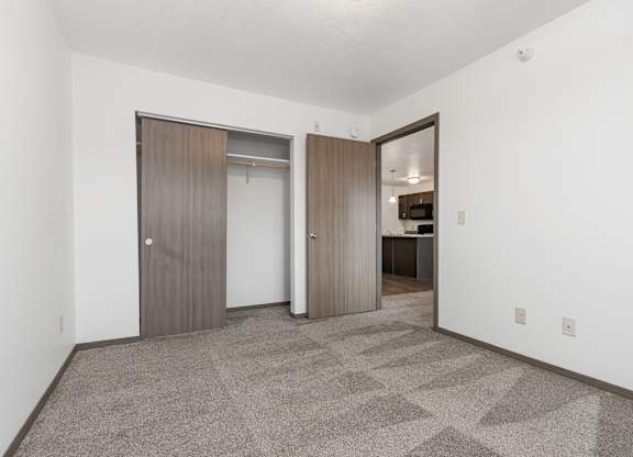 A room with a carpeted floor and two doors.
