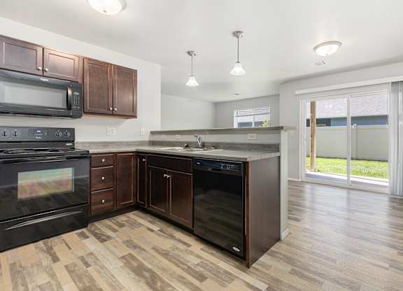 A kitchen with dark wood cabinets and black appliances.