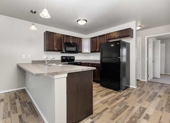 A kitchen with a black refrigerator and wooden cabinets.