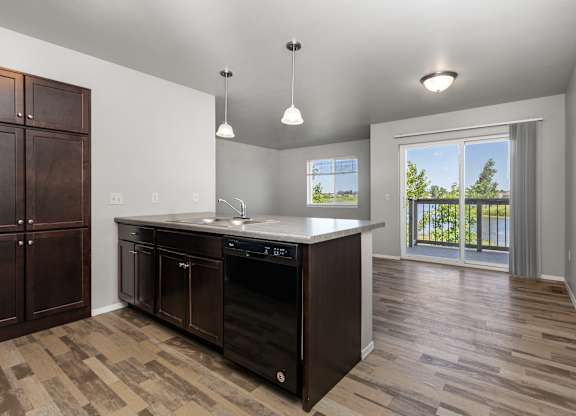 A kitchen with a black dishwasher and wooden cabinets.