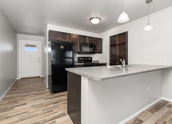A kitchen with a black fridge and microwave.